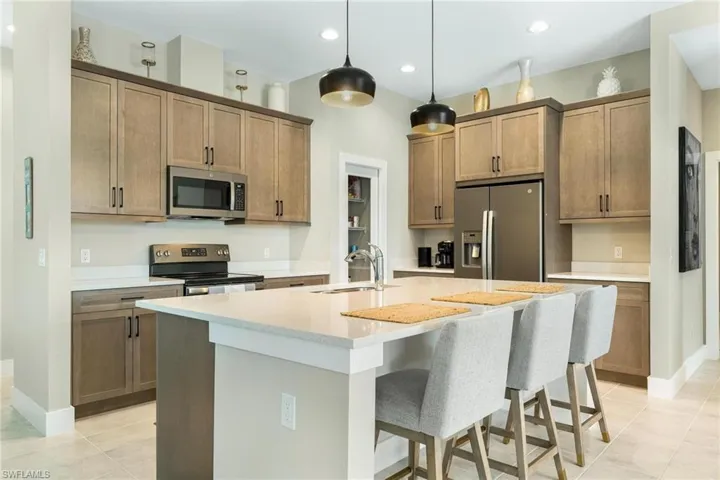 Kitchen featuring sink, light tile patterned flooring, a center island with sink, and stainless steel appliances