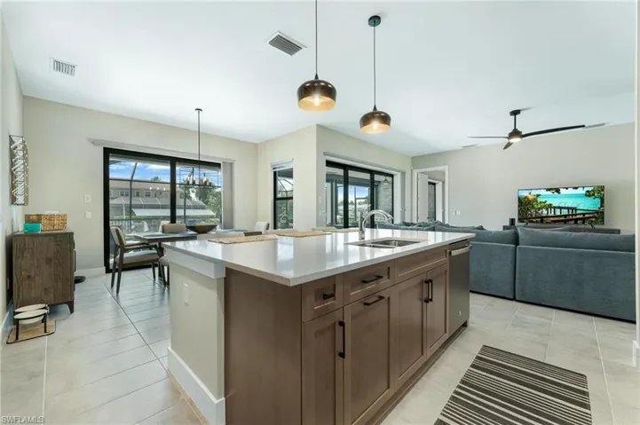 Kitchen with sink, pendant lighting, light tile patterned floors, and an island with sink