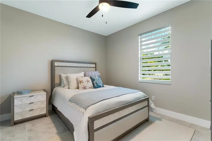 Bedroom featuring multiple windows, ceiling fan, and light tile patterned floors