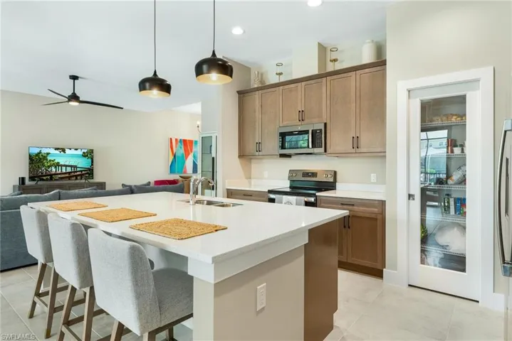 Kitchen featuring sink, appliances with stainless steel finishes, a center island with sink, and light tile patterned floors