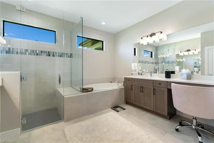 Bathroom featuring tile patterned floors, separate shower and tub, and double vanity