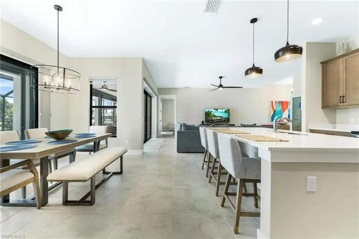 Kitchen featuring pendant lighting, ceiling fan with notable chandelier, a breakfast bar area, and light tile patterned floors