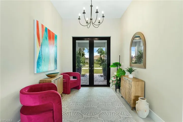 Living area with light tile patterned flooring, a notable chandelier, and french doors