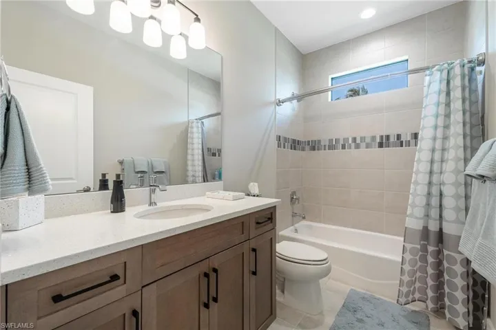 Full bathroom featuring tile patterned flooring, shower / bath combo with shower curtain, toilet, and vanity