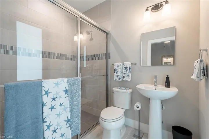 Bathroom with a shower with shower door, toilet, and tile patterned flooring