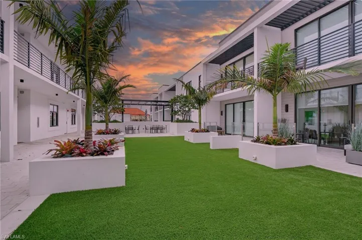 Yard at dusk featuring a patio, a lawn, a balcony, and outdoor dining area