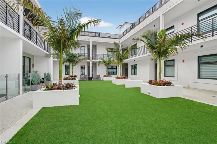 View of grassy yard featuring a patio area and a balcony
