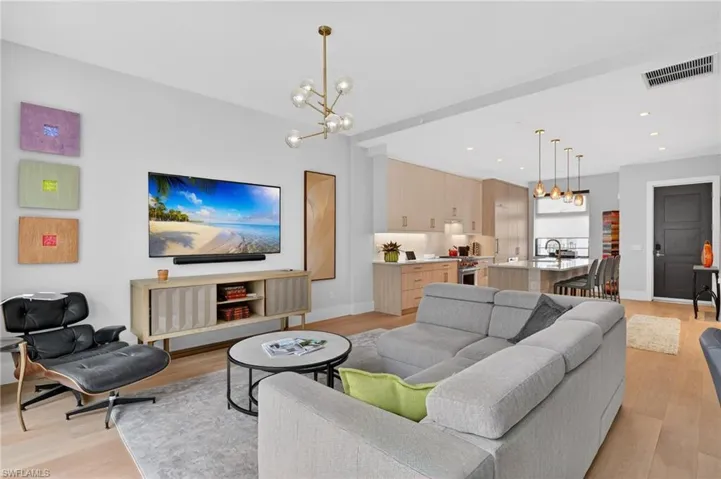 Living room with a chandelier, light wood-type flooring, and recessed lighting