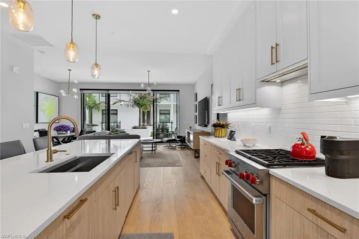 Kitchen with designer range, light stone countertops, hanging light fixtures, light wood-style floors, and a chandelier