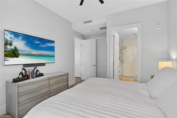 Bedroom featuring ceiling fan, ensuite bath, and light wood finished floors