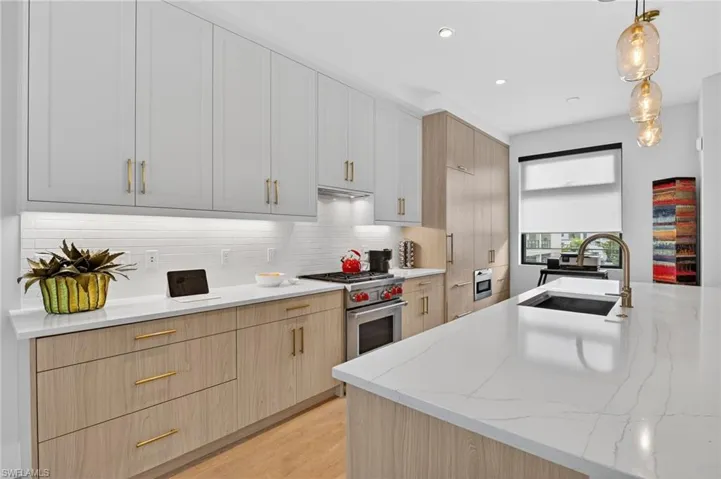 Kitchen with light brown cabinetry, light stone countertops, pendant lighting, modern cabinets, and recessed lighting