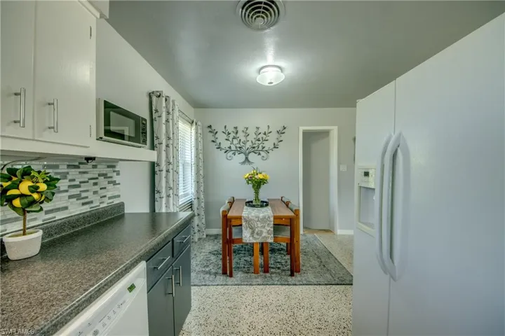 Kitchen featuring backsplash and white appliances