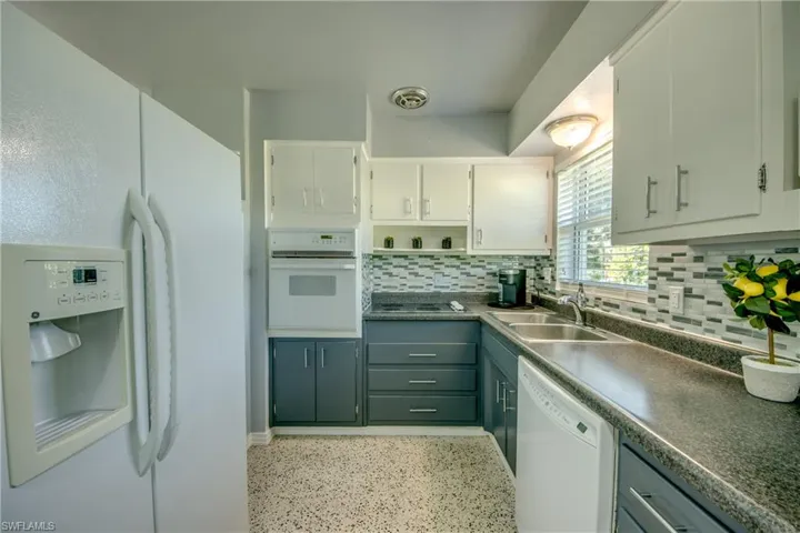 Kitchen featuring sink, white cabinets, white appliances, and backsplash