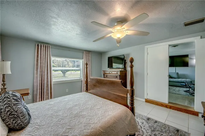 Bedroom featuring a textured ceiling, a closet, tile flooring, and ceiling fan