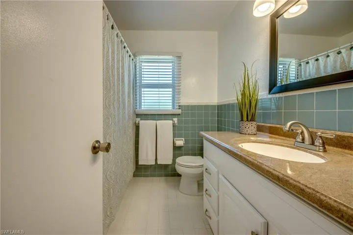 Bathroom with tile walls, backsplash, toilet, tile floors, and large vanity