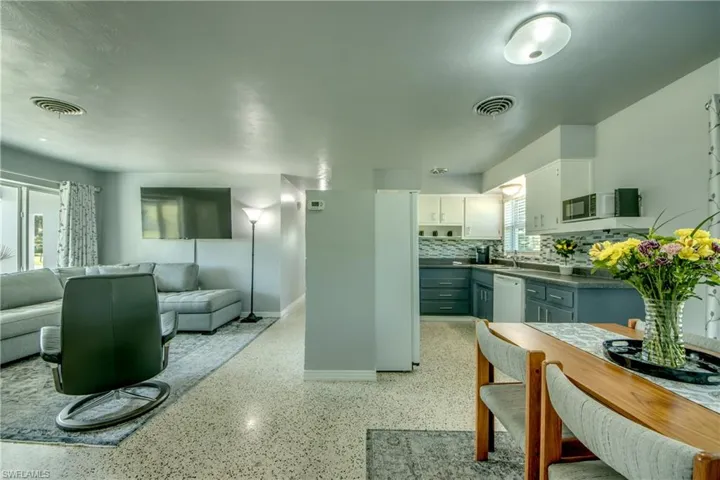 Kitchen with dishwasher, sink, white cabinetry, and backsplash