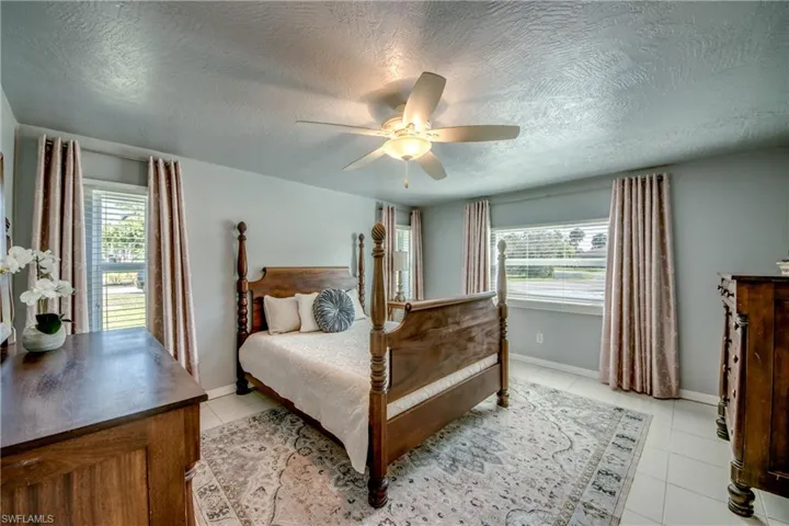 Tiled bedroom with ceiling fan and a textured ceiling