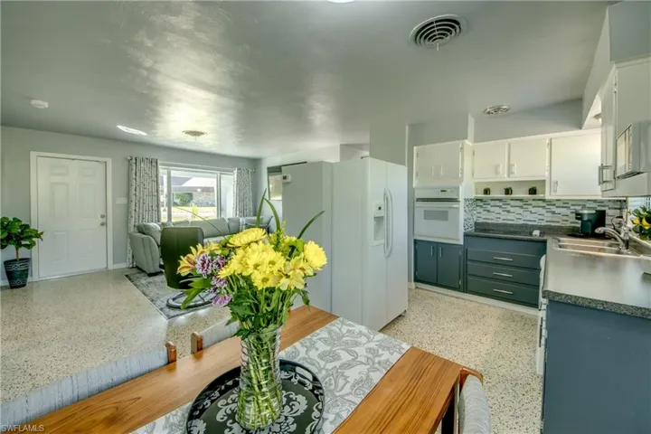 Kitchen featuring white cabinets, sink, white appliances, and tasteful backsplash