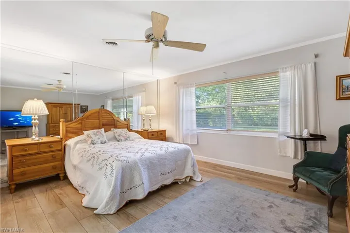 Bedroom with ornamental molding, wood finished floors, and ceiling fan