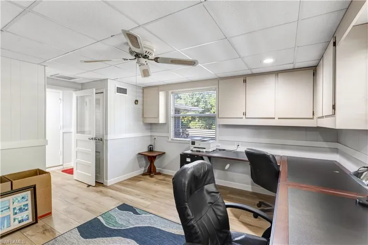 Office space with ceiling fan, a drop ceiling, and light wood-style floors