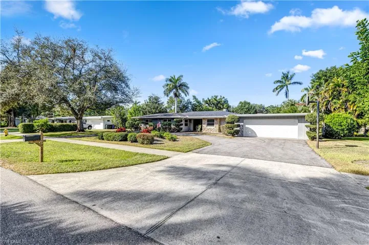 Ranch-style house featuring driveway, a front yard, and a garage