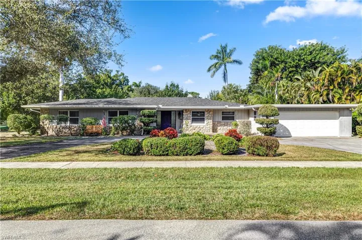 Single story home featuring concrete driveway, stone siding, a front yard, and a garage