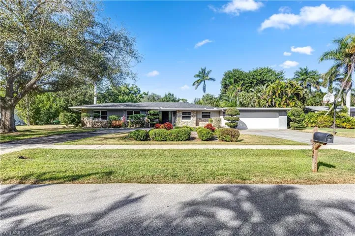 Ranch-style home with concrete driveway, a front lawn, stone siding, and an attached garage
