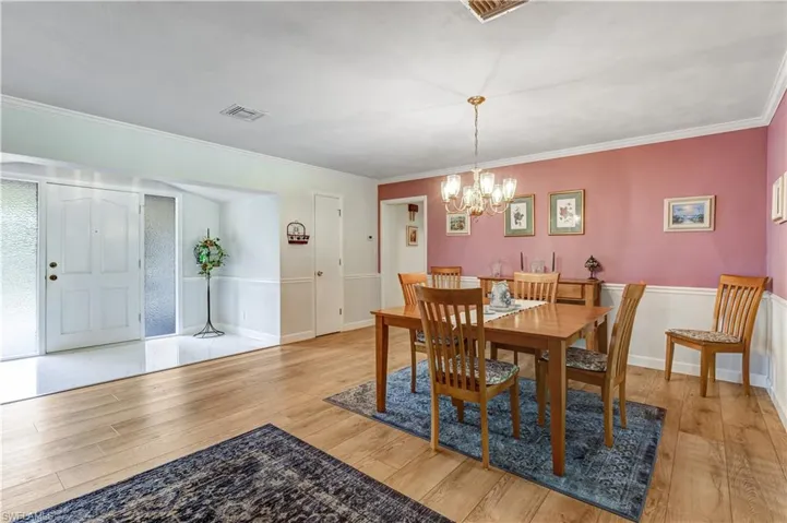 Dining space featuring light wood-style flooring, a chandelier, and ornamental molding