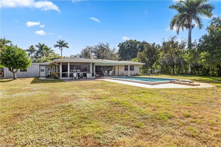 Rear view of house featuring a yard, an outdoor pool, a patio, and a sunroom