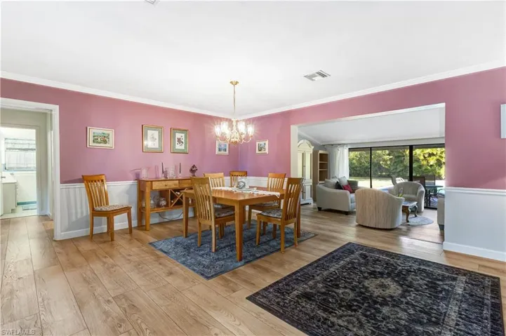 Dining space featuring light wood-style flooring, a chandelier, wainscoting, and ornamental molding