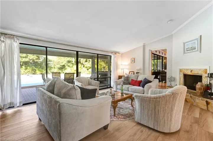 Living room with light wood-style flooring, a premium fireplace, vaulted ceiling, and crown molding