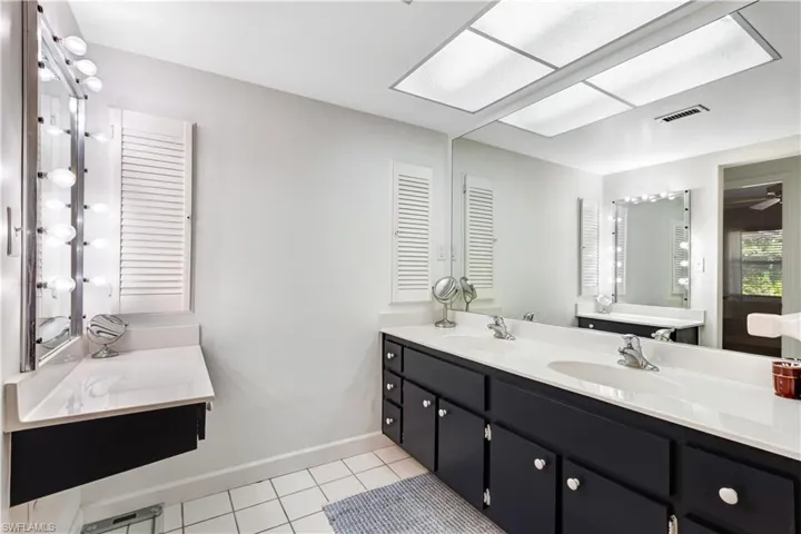 Bathroom with two vanities, double vanity, and light tile patterned flooring