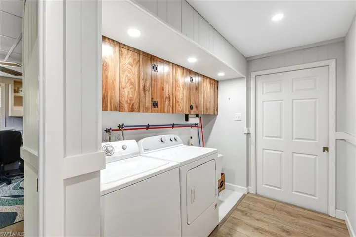Washroom with light wood-type flooring, independent washer and dryer, recessed lighting, a desk, and cabinet space