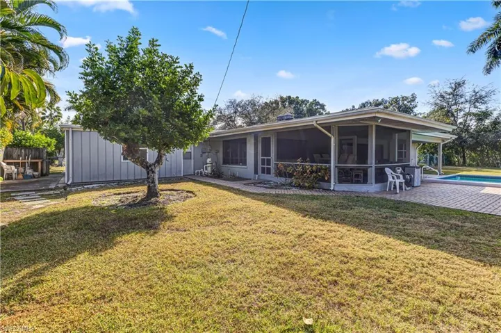 Back of property with a lawn, a sunroom, an outdoor pool, and a patio area