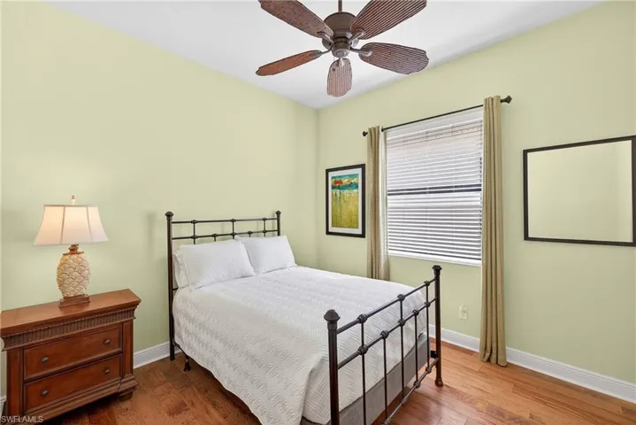 Guest suite with hardwood floors, ceiling fan, and large window, offering natural light