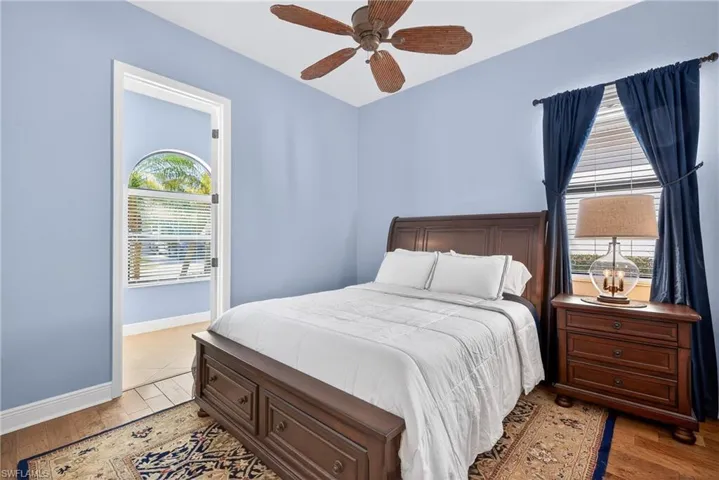 Guest suite with engineered hardwood floors, ceiling fan, large window, and attached full bath.