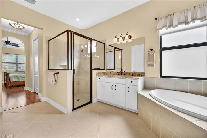 Primary ensuite bath with dual vanities, soaking tub, glass-enclosed walk-in shower, and abundant natural light, private water closet, linen closet and upgraded diagonal tiles
