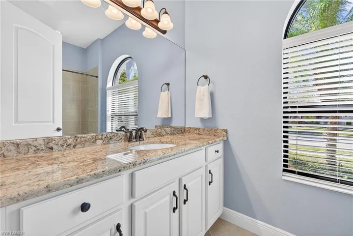 Ensuite bathroom with quartz counter vanity, tiled tub/shower combo, neutral finishes, and natural light