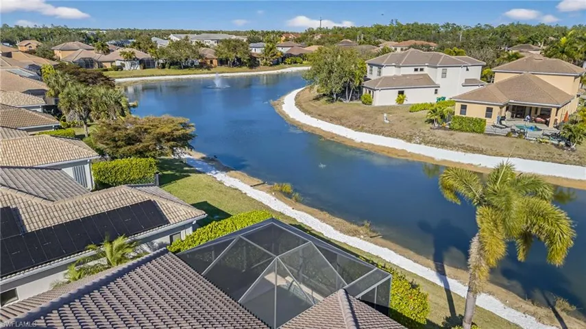 Aerial view of lakefront Naples pool home in X500 no flood zone featuring heated pool, southwestern exposure, and seamless indoor-outdoor living in a gated community