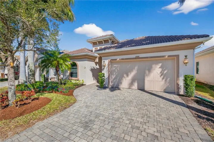 Naples Florida pool home with two-car garage, paver driveway, tile roof, and manicured landscaping in preferred X500 flood zone.