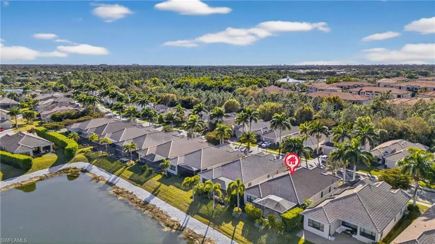 Aerial view of lakefront Naples pool home in X500 no flood zone featuring heated pool, southwestern exposure, and seamless indoor-outdoor living in a gated community