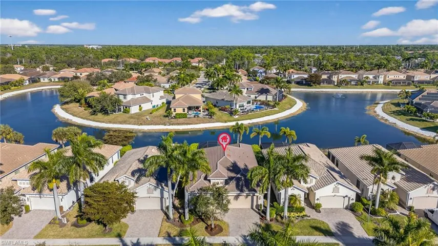 Aerial view of lakefront Naples pool home in X500 no flood zone featuring heated pool, southwestern exposure, and seamless indoor-outdoor living in a gated community
