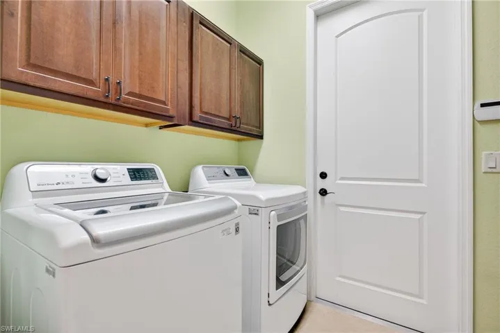 Dedicated laundry room with upper cabinetry for storage and full-size washer and dryer