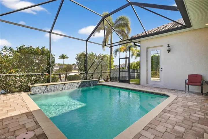 Southwestern-exposure screened lanai featuring heated pool, water features, lake views, and enhanced tropical landscaping for privacy