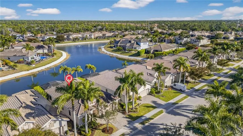 Aerial view of lakefront Naples pool home in X500 no flood zone featuring heated pool, southwestern exposure, and seamless indoor-outdoor living in a gated community