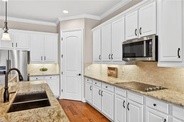Open kitchen featuring pendant lighting, white cabinetry, stainless steel appliances, and crown molding, and walk-in pantry