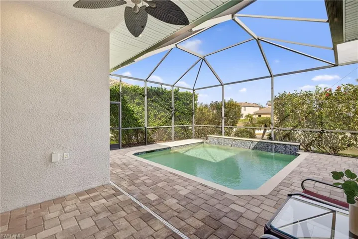 Southwestern-exposure screened lanai with under roof dining area, featuring heated pool, water features, lake views, and enhanced tropical landscaping for privacy