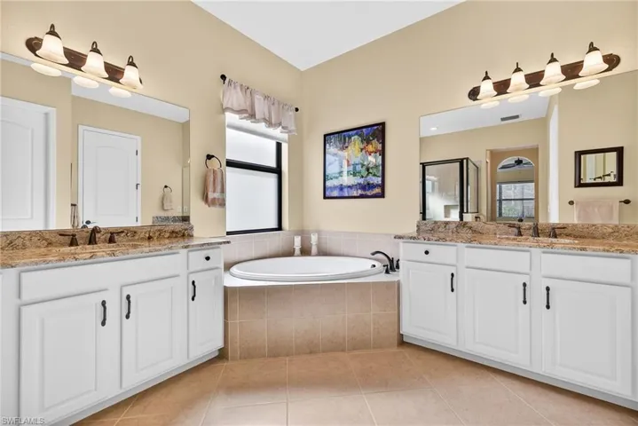 Primary ensuite bath with dual vanities, soaking tub, glass-enclosed walk-in shower, and abundant natural light, private water closet, linen closet and upgraded diagonal tiles