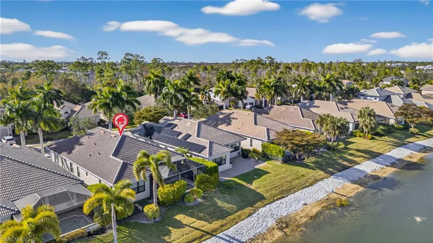 Aerial view of lakefront Naples pool home in X500 no flood zone featuring heated pool, southwestern exposure, and seamless indoor-outdoor living in a gated community