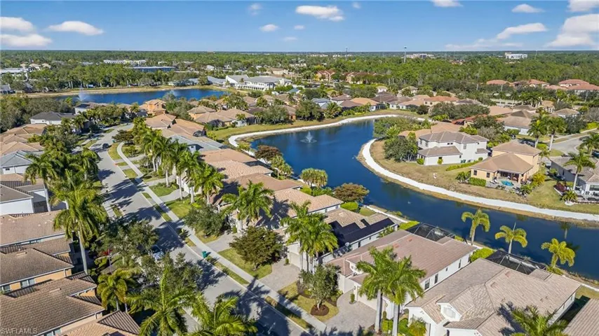 Aerial view of lakefront Naples pool home in X500 no flood zone featuring heated pool, southwestern exposure, and seamless indoor-outdoor living in a gated community